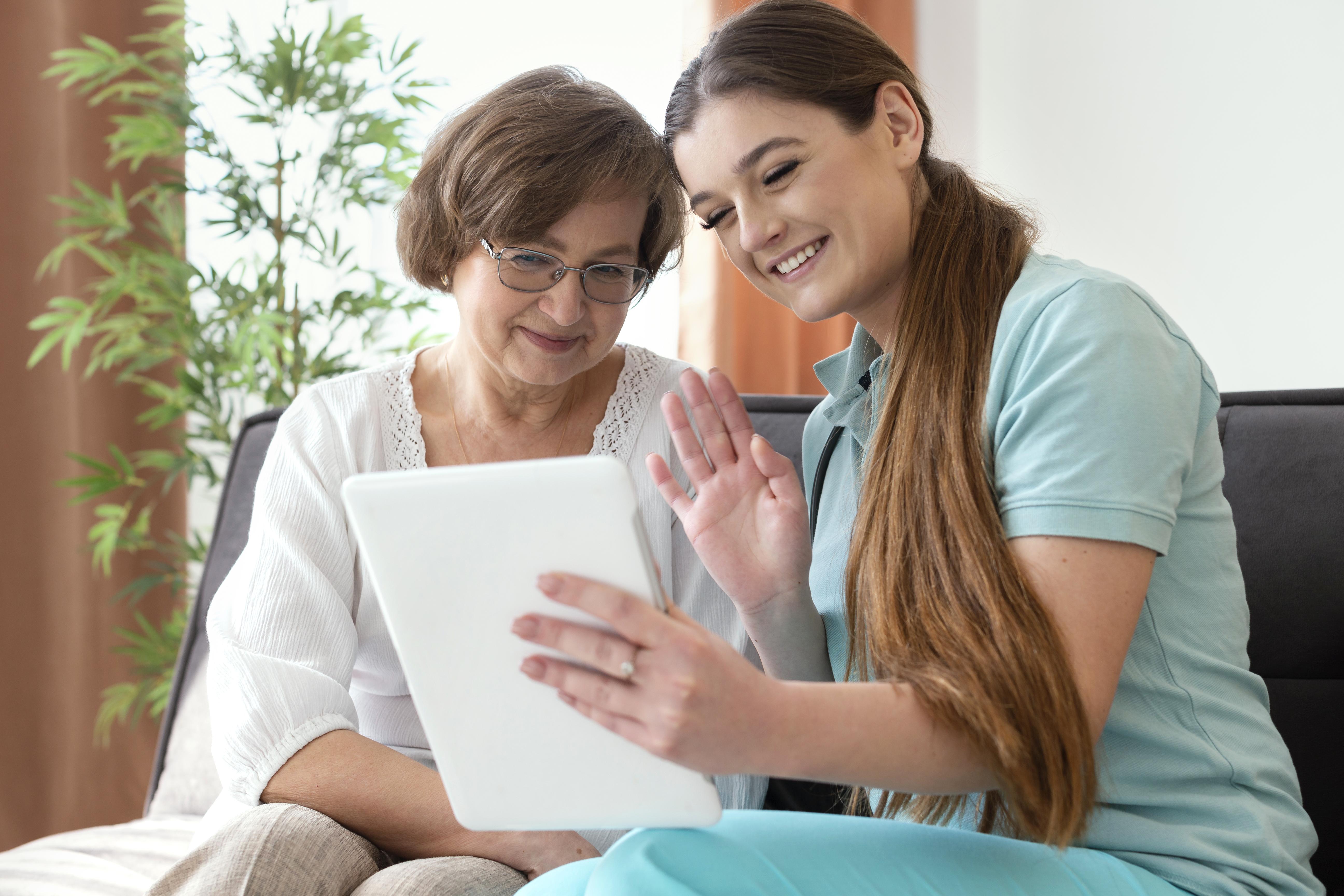 Caregiver helping elderly person with tablet